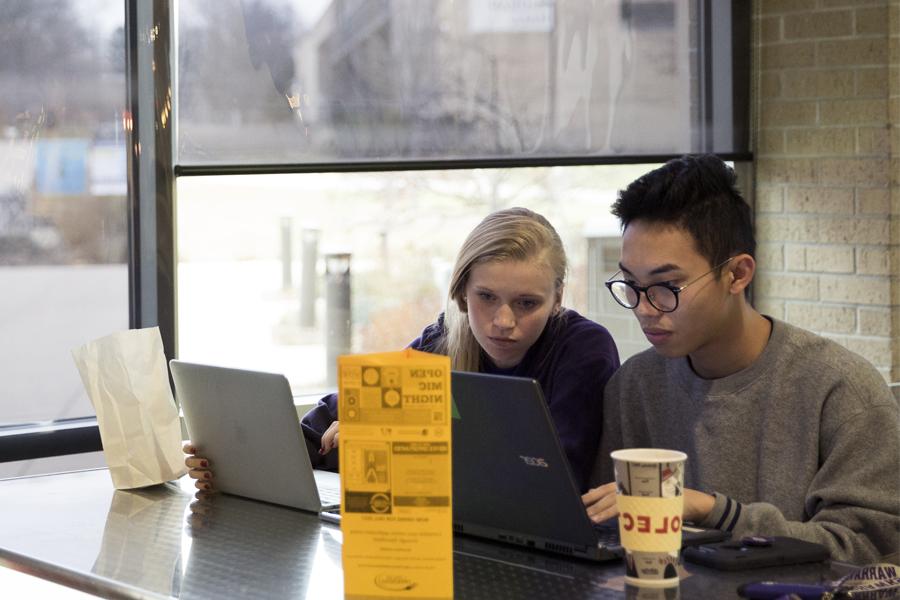 Two students work on a laptop by a window in the University Center.