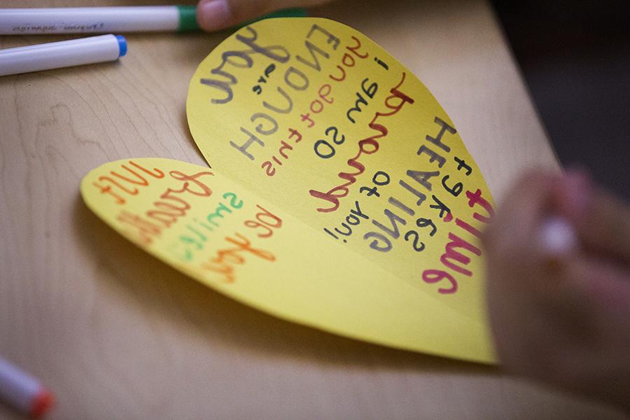 A heart is cut out of yellow paper with positive affirmations written on it in marker.